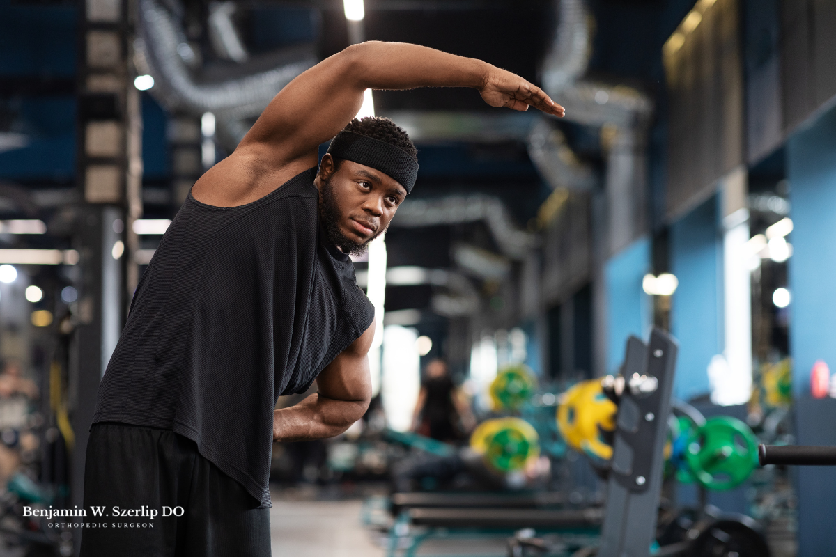 A man stretching before weightlifting at the gym to avoid getting injured in Texas.