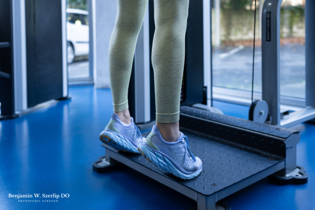 A woman performing a standing heel raise after regaining strength and mobility in her ankle after an Achilles Tendon Repair in Texas.