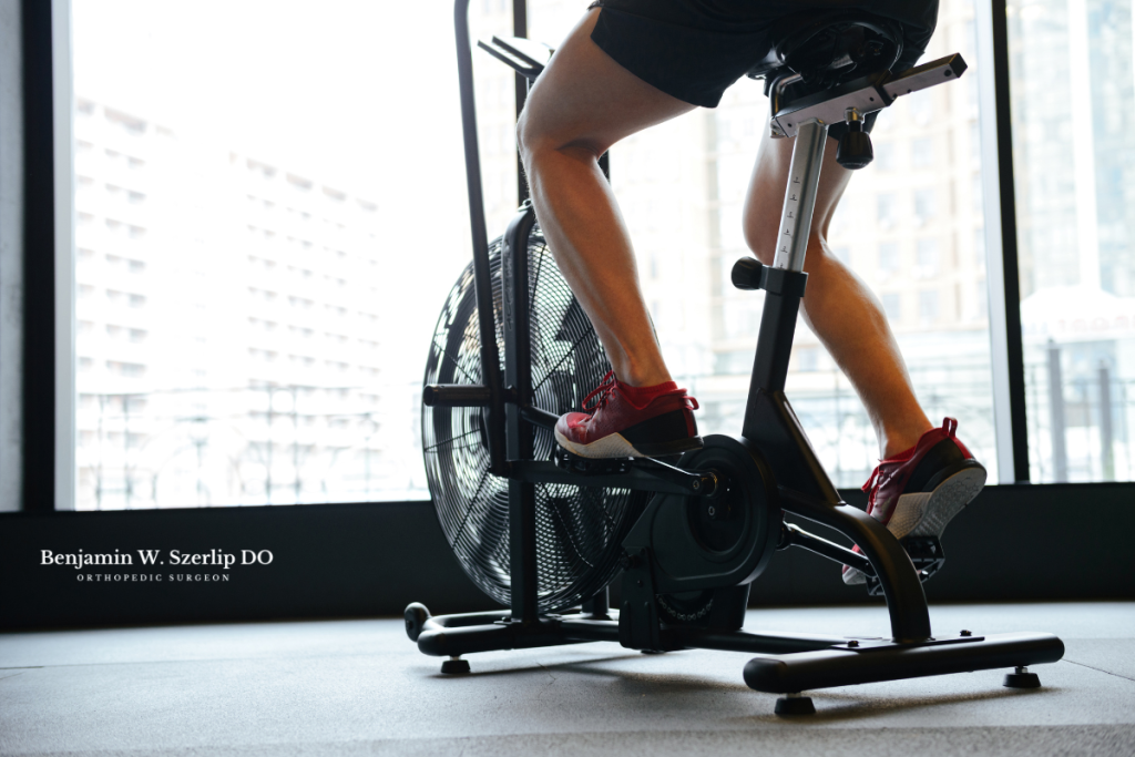 A man using a stationary bike to increase mobility to help in recovery after a patellar tendon tear in Texas.