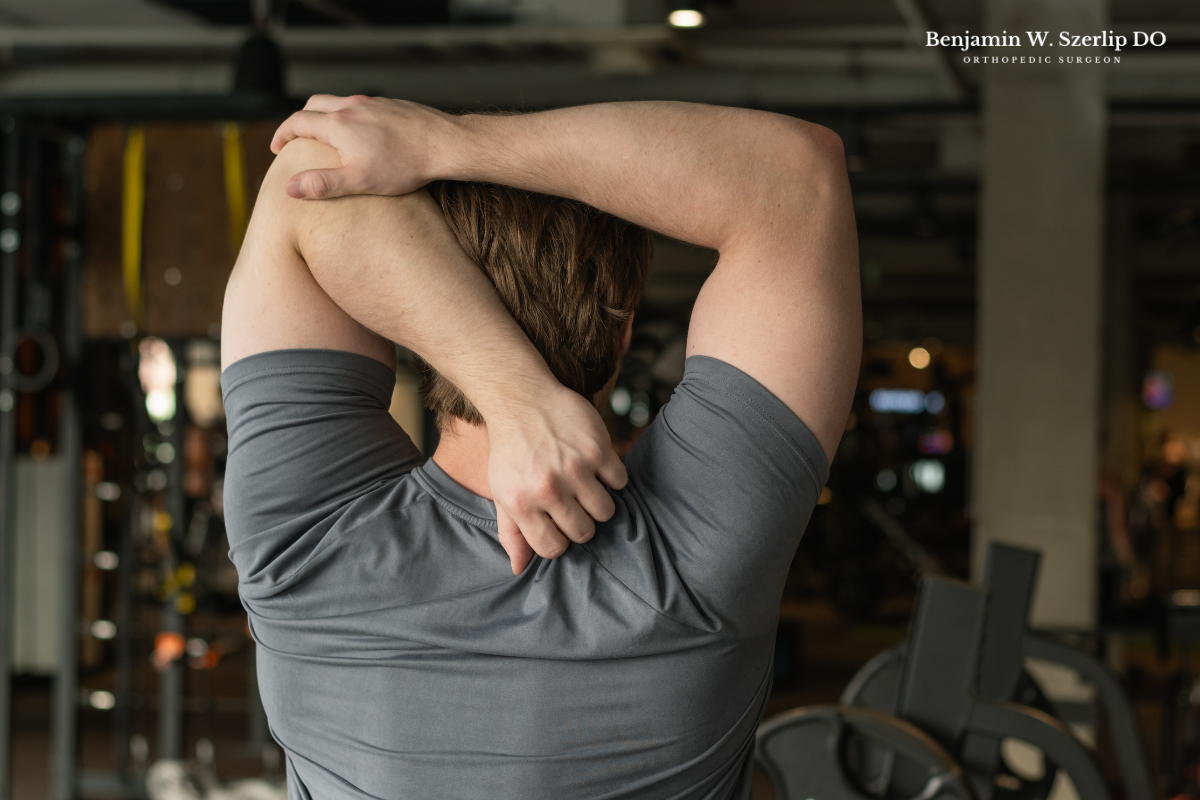 A man stretching his shoulder at the gym after fully recovering from a fracture in Texas.